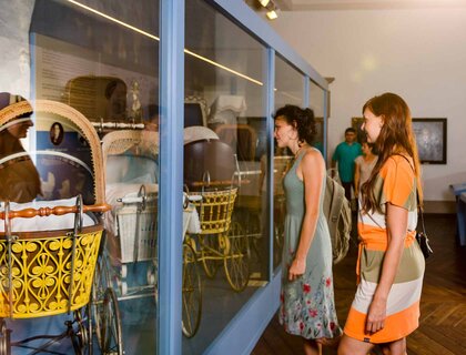 Besuchende im Kinderwagenmuseum Zeitz bestaunen alte Kinderwagenmodelle