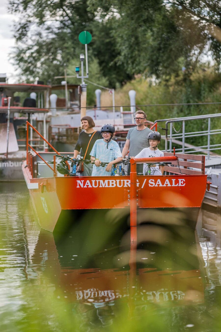 Familie mit Fahrrädern nutzt die Fähre über den Fluss im Naumburger Blütengrund