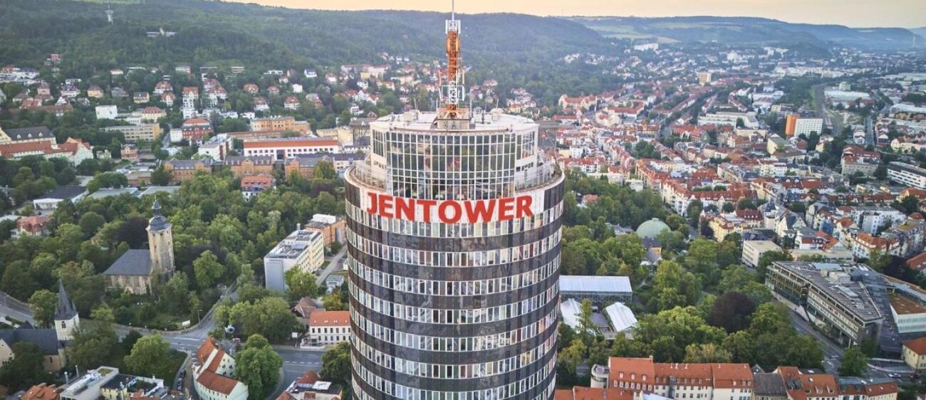 Der JenTower in Jena wird aus der Vogelperspektive gezeigt. Zu sehen ist ein roter sSchriftzug mit dem Wort Jentower.