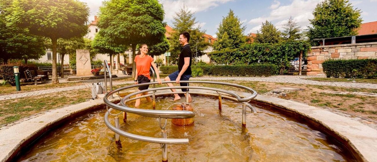 Zwei Personen die durch das Kneippbecken in Bad Bibra laufen.