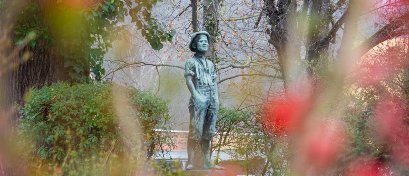 lustige Jungenfigur mit Hut im Stadtpark Weißenfels mit Frühlingsblüten